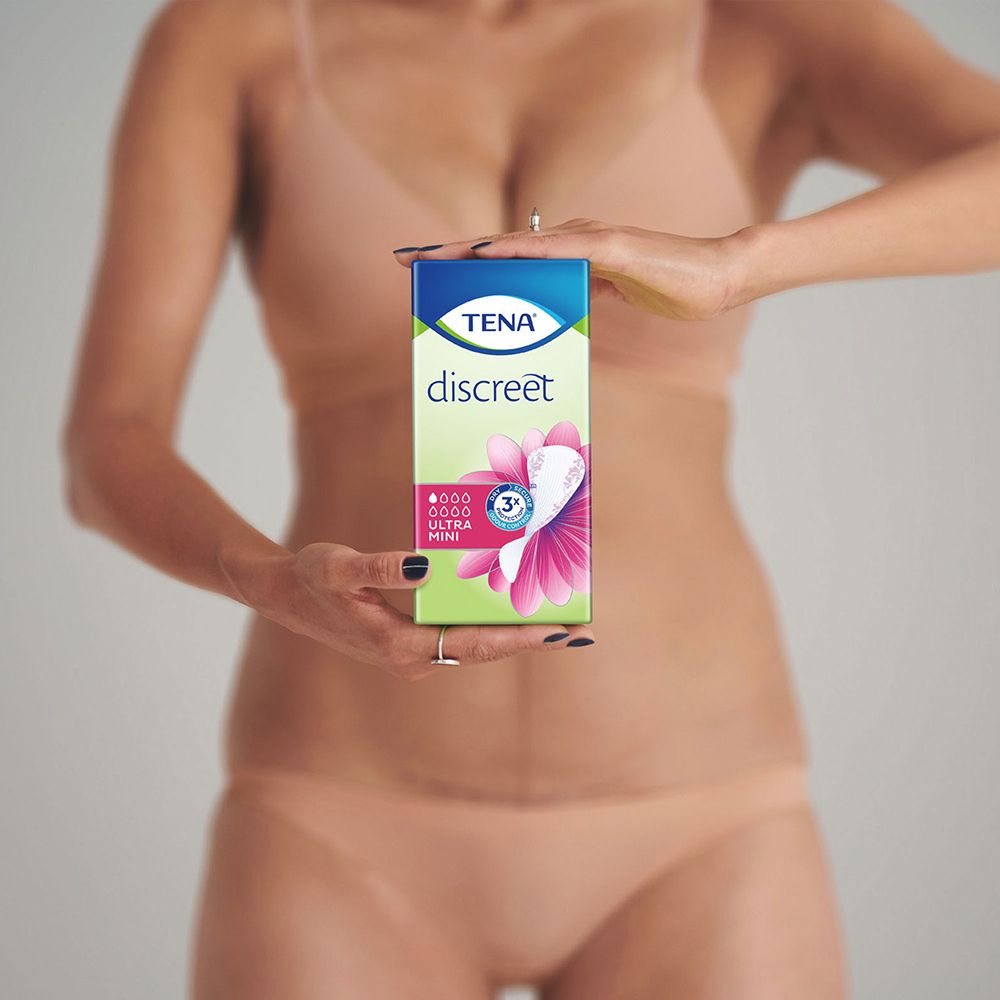 Persona tiene un pacco TENA discreet Ultra Mini. Confezione con immagine del prodotto. La persona indossa biancheria intima.