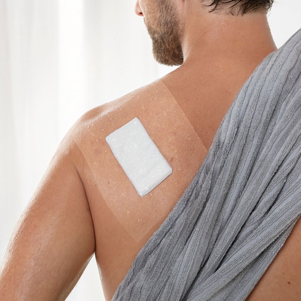 Un uomo con una medicazione trasparente sulla schiena. La medicazione è rettangolare e trasparente.