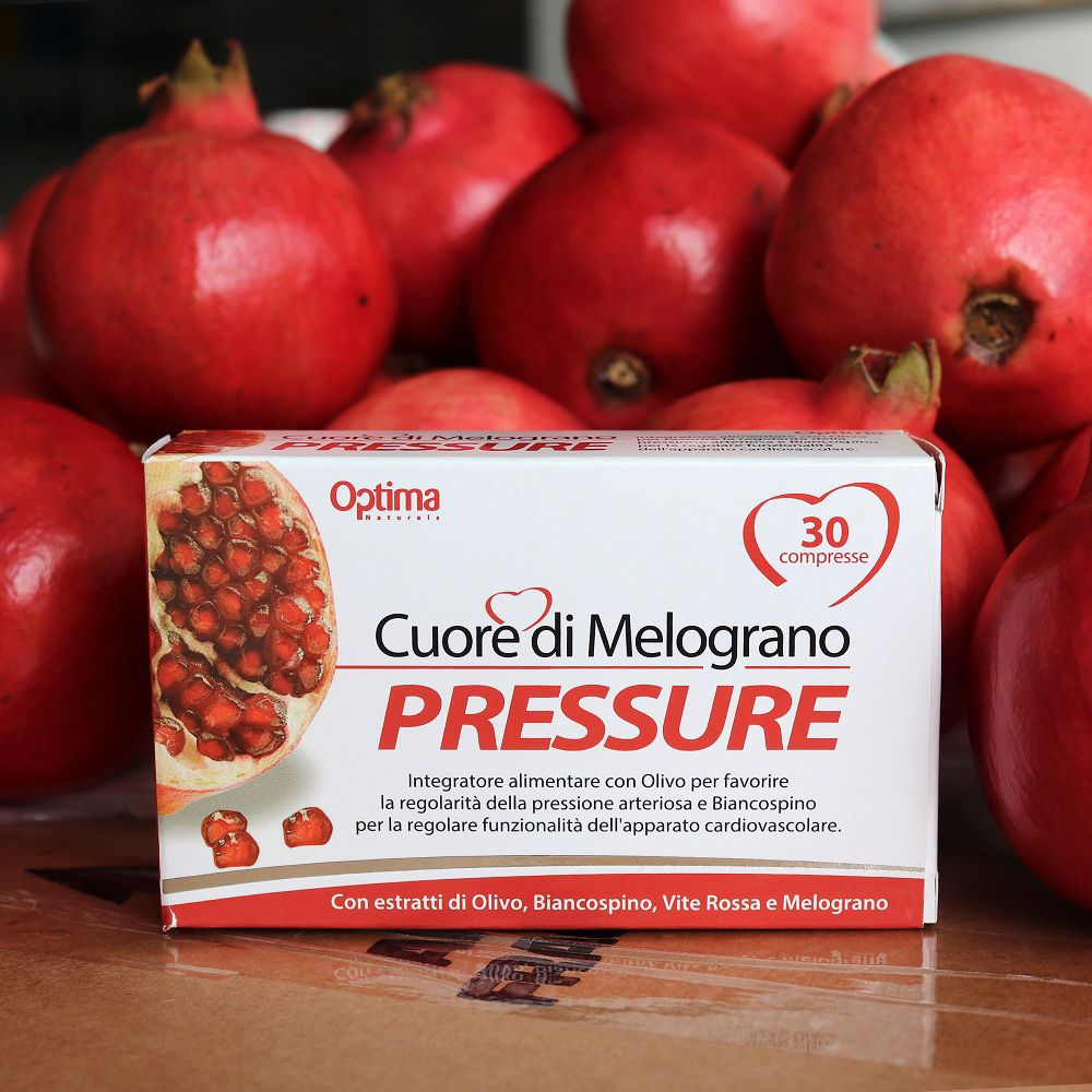 Confezione Optima Cuore di Melograno PRESSURE in mezzo a melograni freschi.