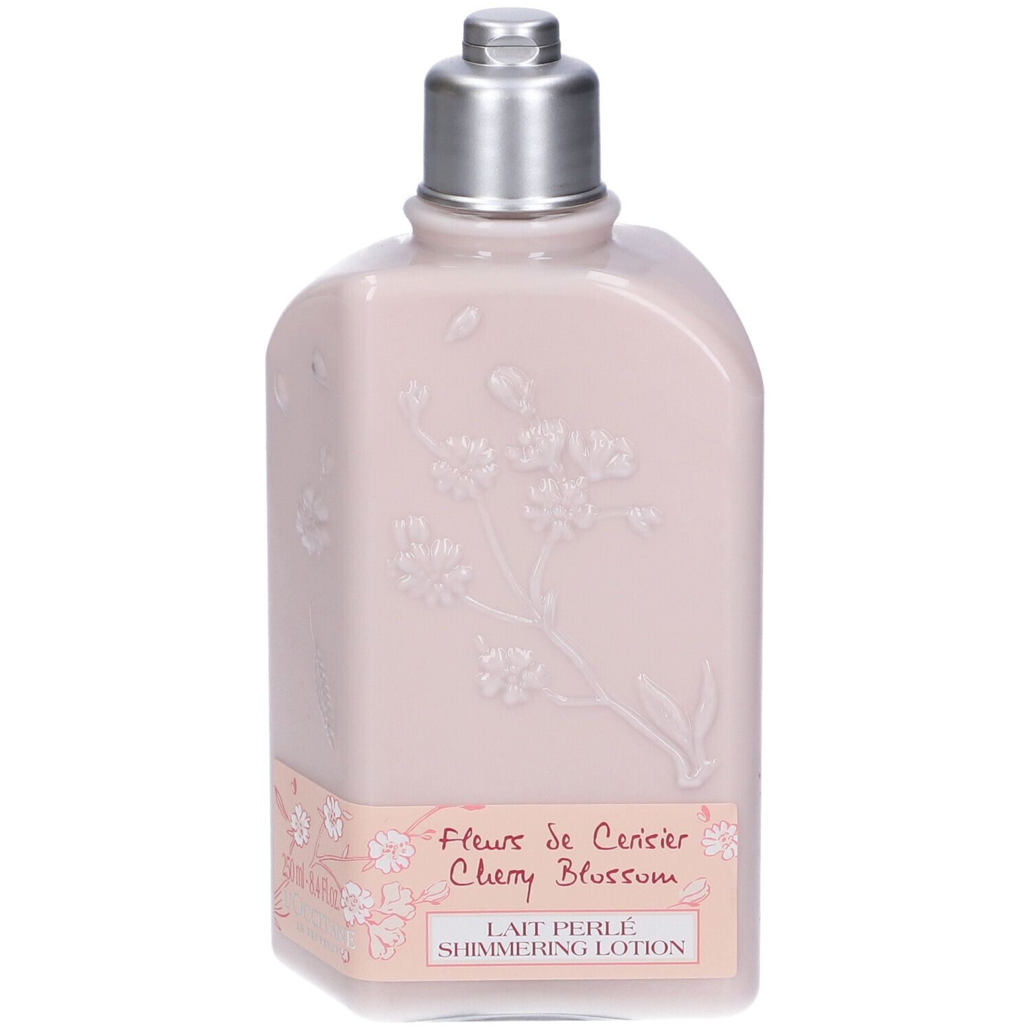 Flacone rosa con tappo argentato. Rilievo floreale ed etichetta con testo. L'Occitane.