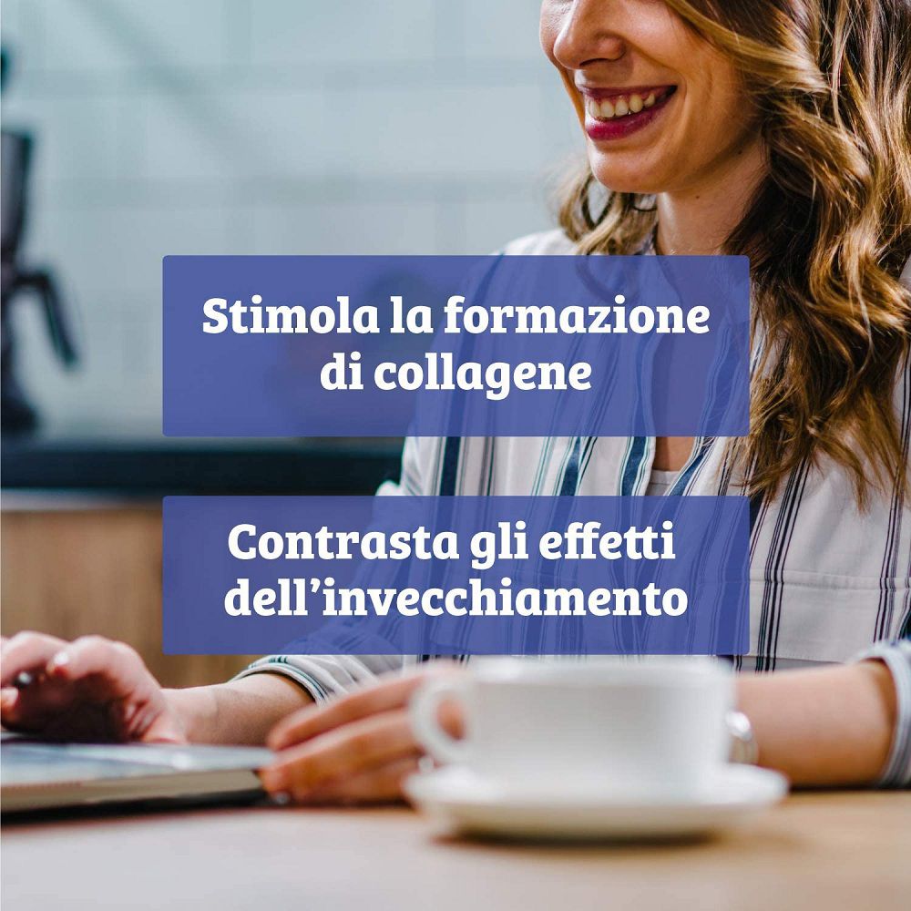 Donna sorridente al laptop, tazza di caffè accanto. Testo: Stimola la formazione di collagene, contrasta l'invecchiamento.