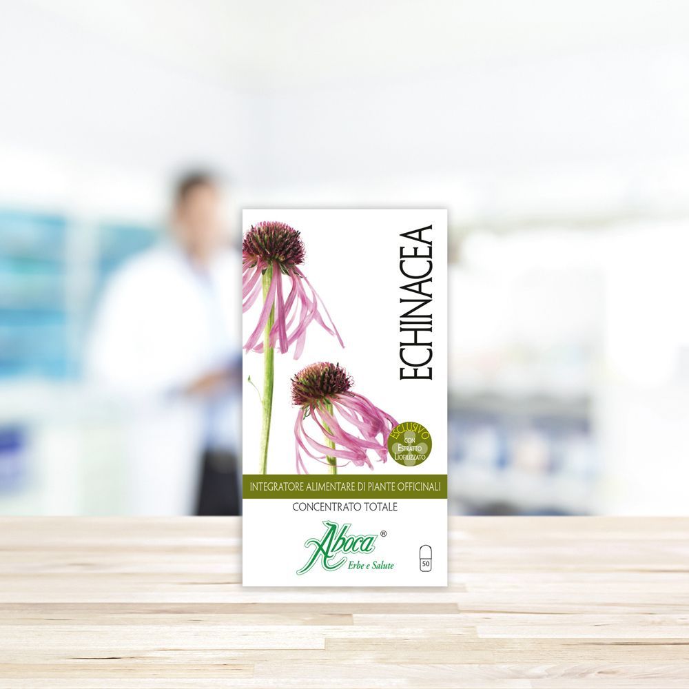 Scatola con fiori di echinacea. Testo: ECHINACEA, Integratore Alimentare. Sfondo: farmacia sfocata.