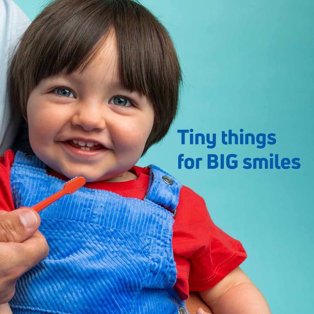 Un bambino sorride mentre gli vengono lavati i denti.