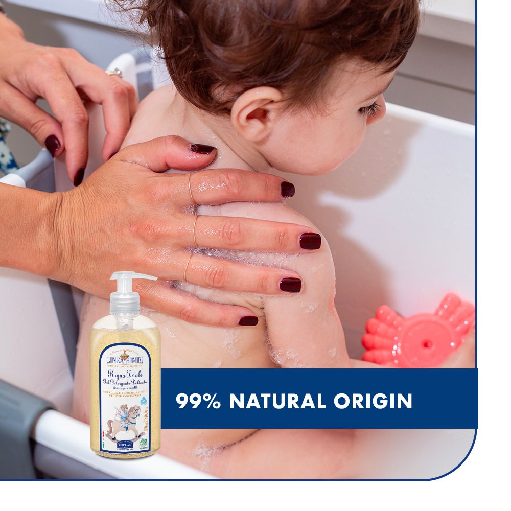 Bambino nella vasca da bagno, la madre lava. Flacone: LINEA BIMBI, Bagno Totale. Testo: 99% origine naturale.
