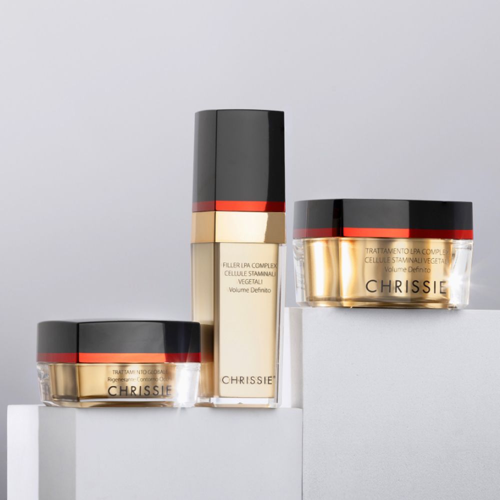 Tre prodotti cosmetici: vasetto, flacone e vasetto. Coperchi neri, fasce rosse. Scritta: Chrissie, Trattamento Globale.