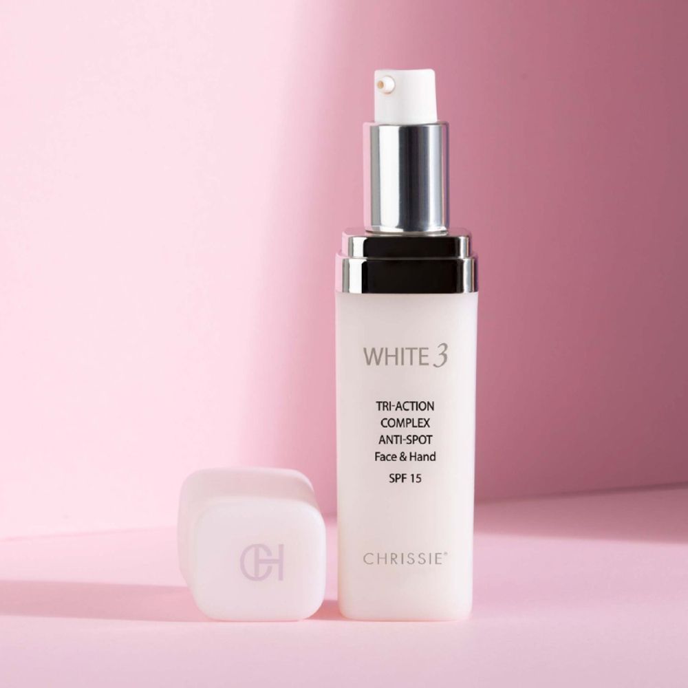 Flacone bianco White 3 Tri-Action Complex Anti-Macchie Viso & Mani SPF 15. Tappo accanto. Chrissie.