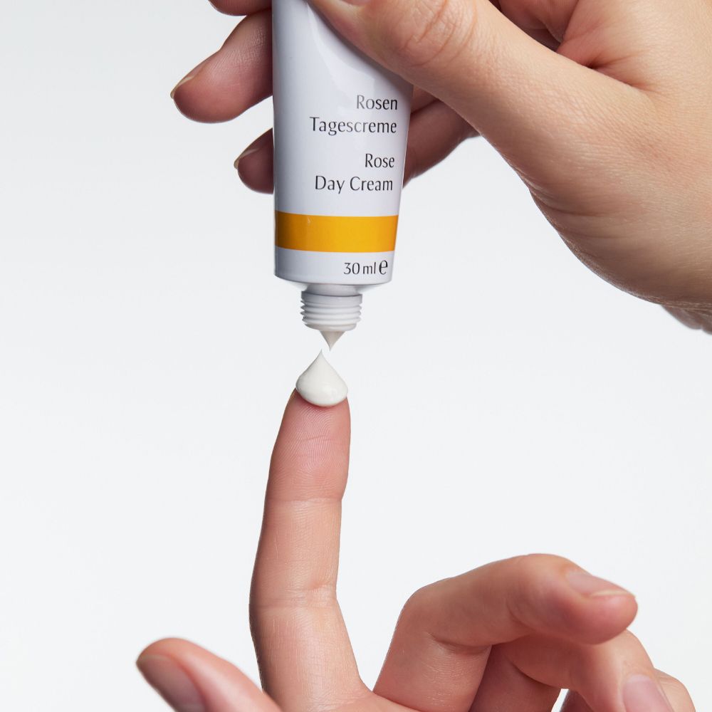 Mano che preme la crema da un tubetto su un dito. Scritta: Rose Day Cream, 30ml.