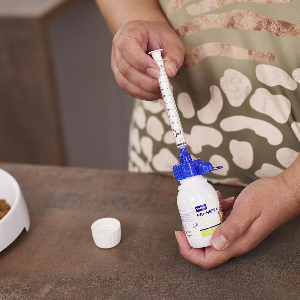 Una persona tiene in mano una bottiglia e una siringa. Bottiglia con tappo blu. La siringa è piena.