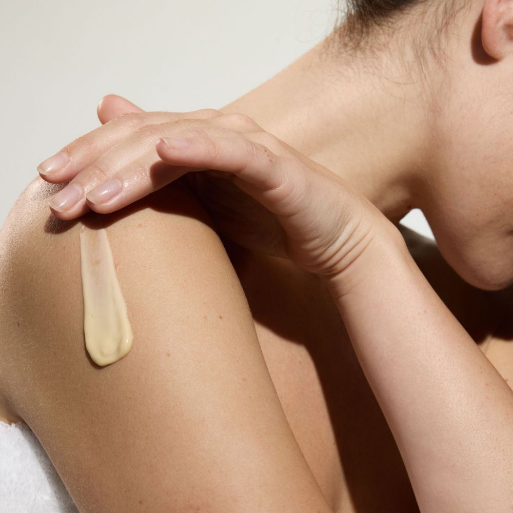 Persona applica crema sulla spalla. Macchia di crema sulla pelle.