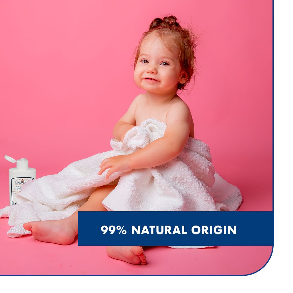 Bambina avvolta in un asciugamano, con un flacone. Testo: 99% origine naturale. Sfondo rosa.
