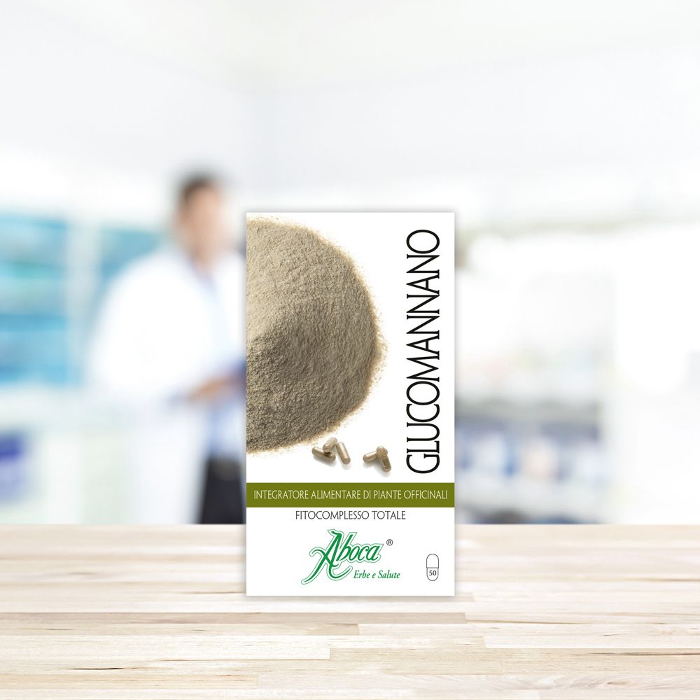 Confezione del prodotto su tavolo in legno. Scritto: Glucomannano, Aboca. Sfondo: farmacia sfocata.