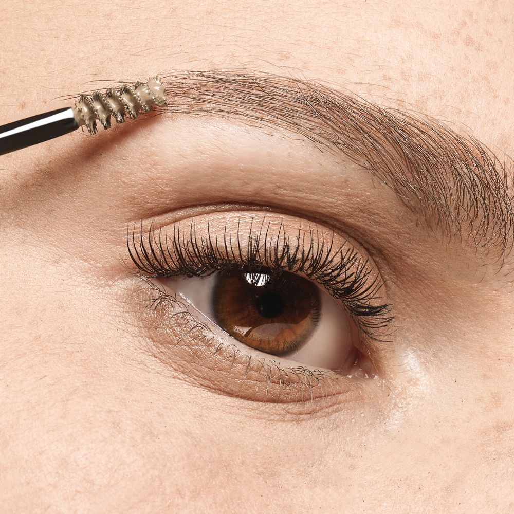 Occhio con sopracciglia lavorate con un pennello. Il pennello è rivestito di prodotto.