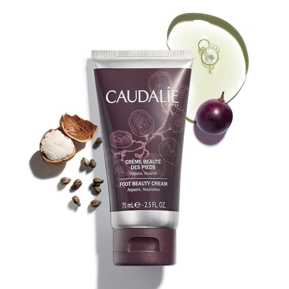 Tubo di crema CAUDALIE con elementi: uva, olio, noci e semi. Testo: CRÈME BEAUTÉ DES PIEDS, FOOT BEAUTY CREAM.