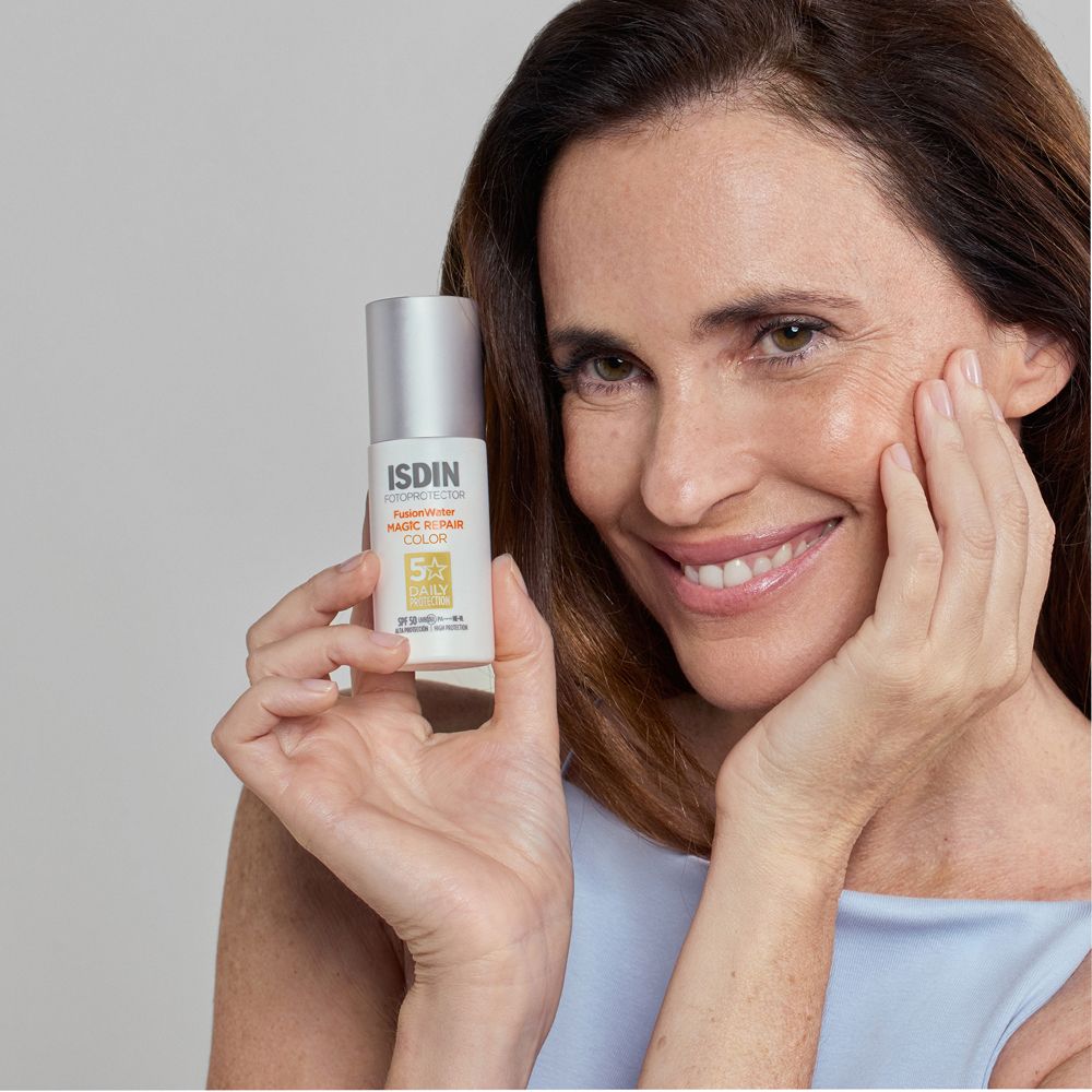 Donna con ISDIN Fotoprotector Fusion Water Magic Repair Color Spray SPF 50. Pelle chiara, sorriso.
