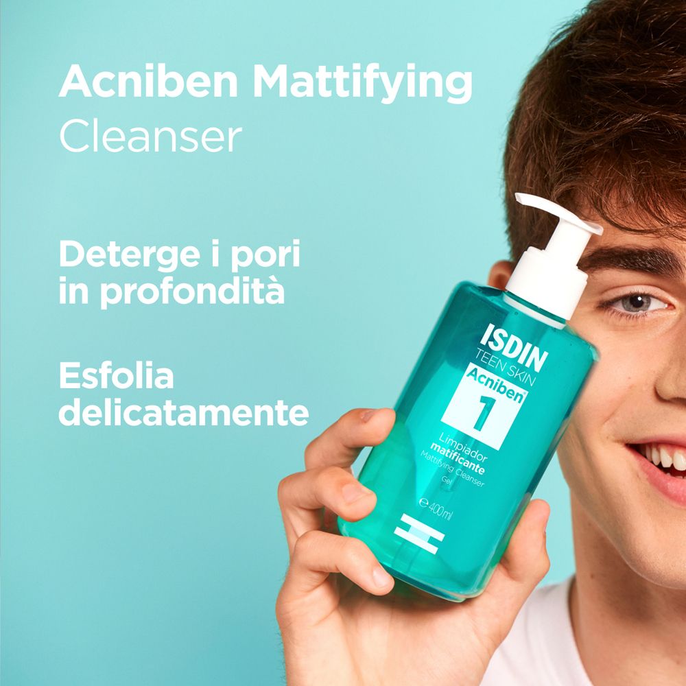 Giovane uomo tiene in mano un flacone turchese. Scritta: ISDIN Teen Skin Acniben 1, gel detergente opacizzante.