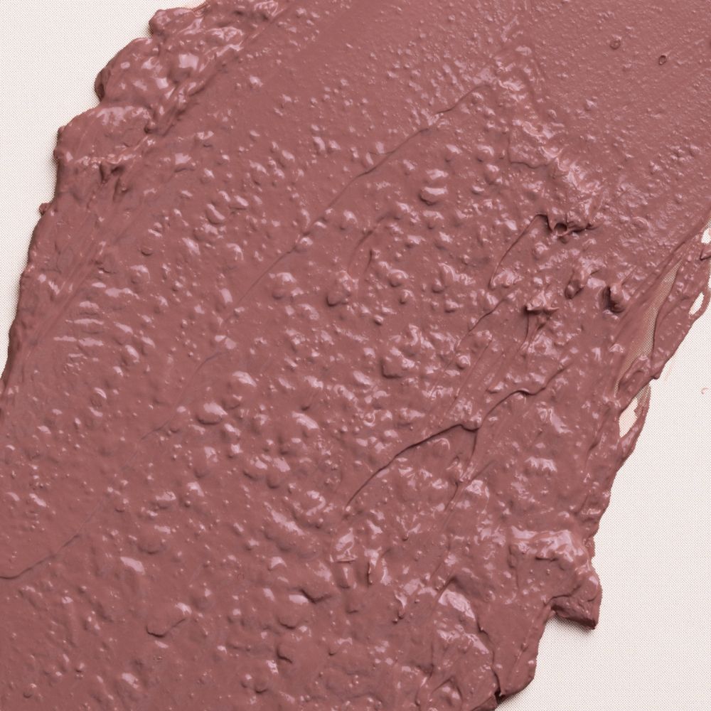 Primo piano di un campione di rossetto color crema. La texture è irregolare e di colore beige-rosa.