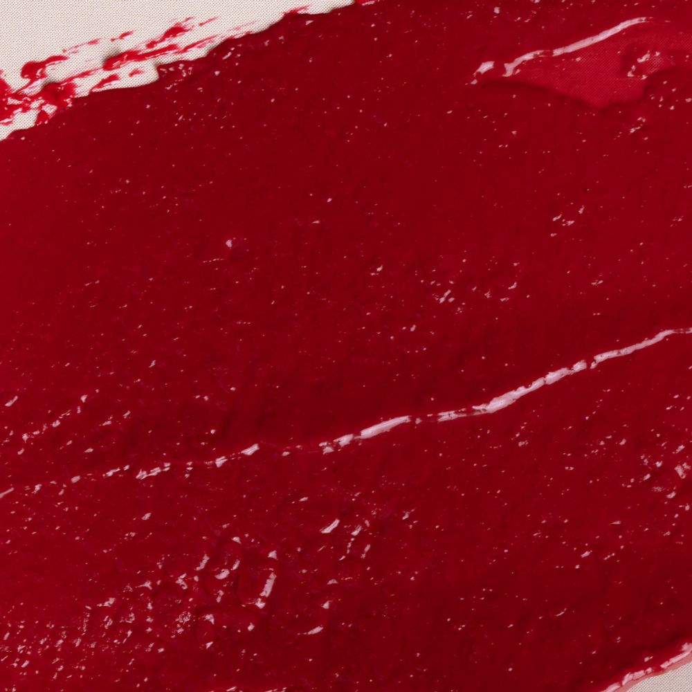 Primo piano di una striscia di rossetto rosso. La texture è lucida e irregolare.