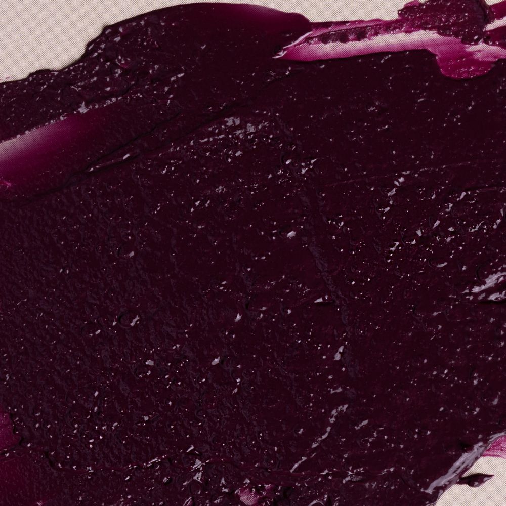 Primo piano di un campione di rossetto bordeaux. La texture è lucida e cremosa.