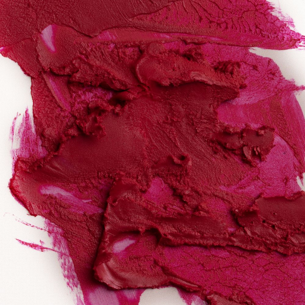 Primo piano di rossetto rosso. Consistenza cremosa, irregolare. Tonalità rosso intenso.