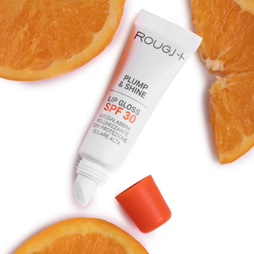 Rougj Plump & Shine lucidalabbra. Tubetto bianco, tappo arancione. Testo: SPF 30, Lucidalabbra volumizzante. Fette d'arancia.