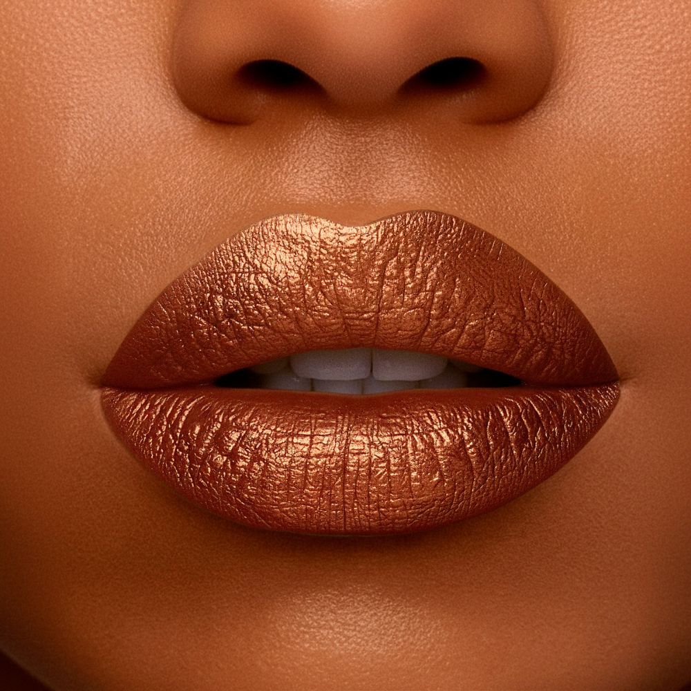 Primo piano di labbra coperte di rossetto dorato metallizzato. Le labbra sono piene.