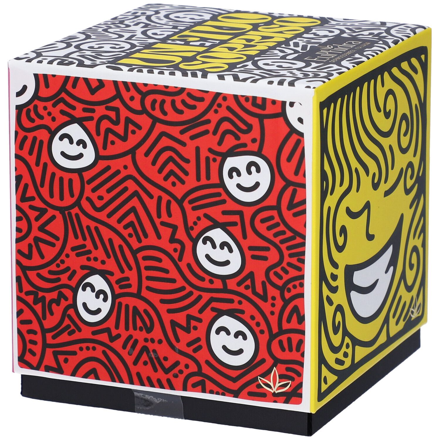 Scatola regalo quadrata con motivi rossi e gialli. Scritta 'Un Tuo Sorriso'. Base nera.