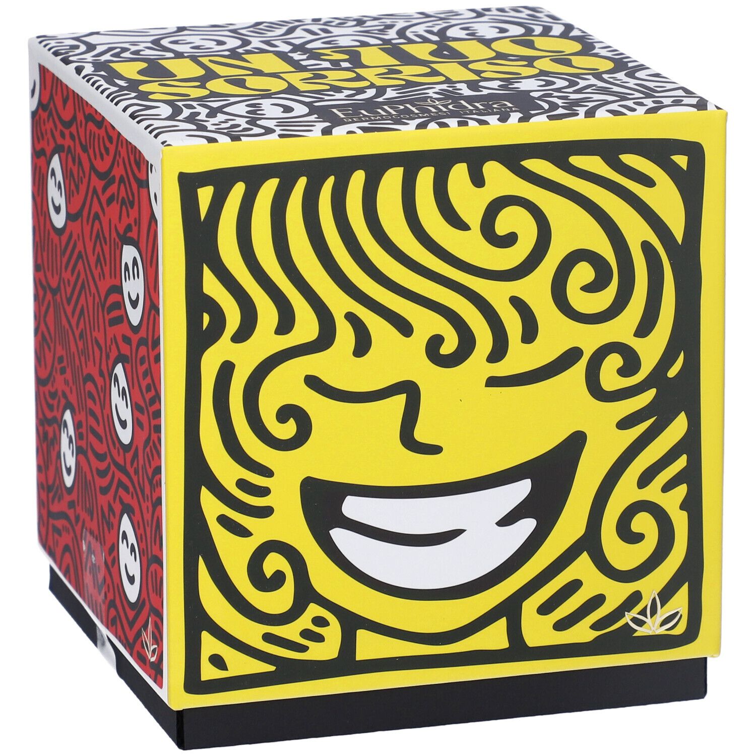Scatola regalo quadrata con volto giallo e motivi rossi. Scritta 'Un Tuo Sorriso'.