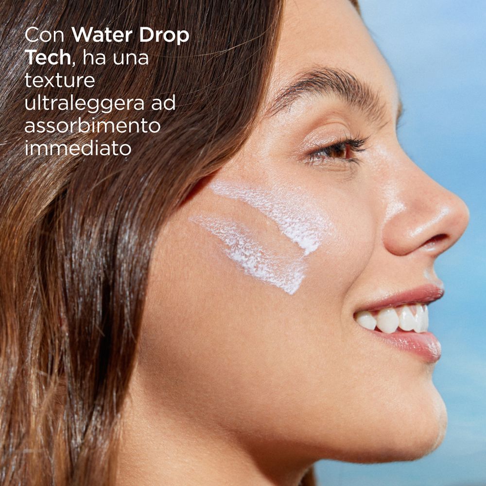 Primo piano di una donna. Sulla pelle strisce di crema solare bianca. Testo: Con Water Drop Tech.