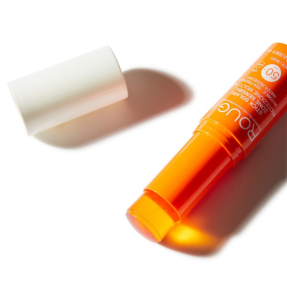 Stick solare arancione con tappo bianco. Dettagli del prodotto visibili. SPF 50+.