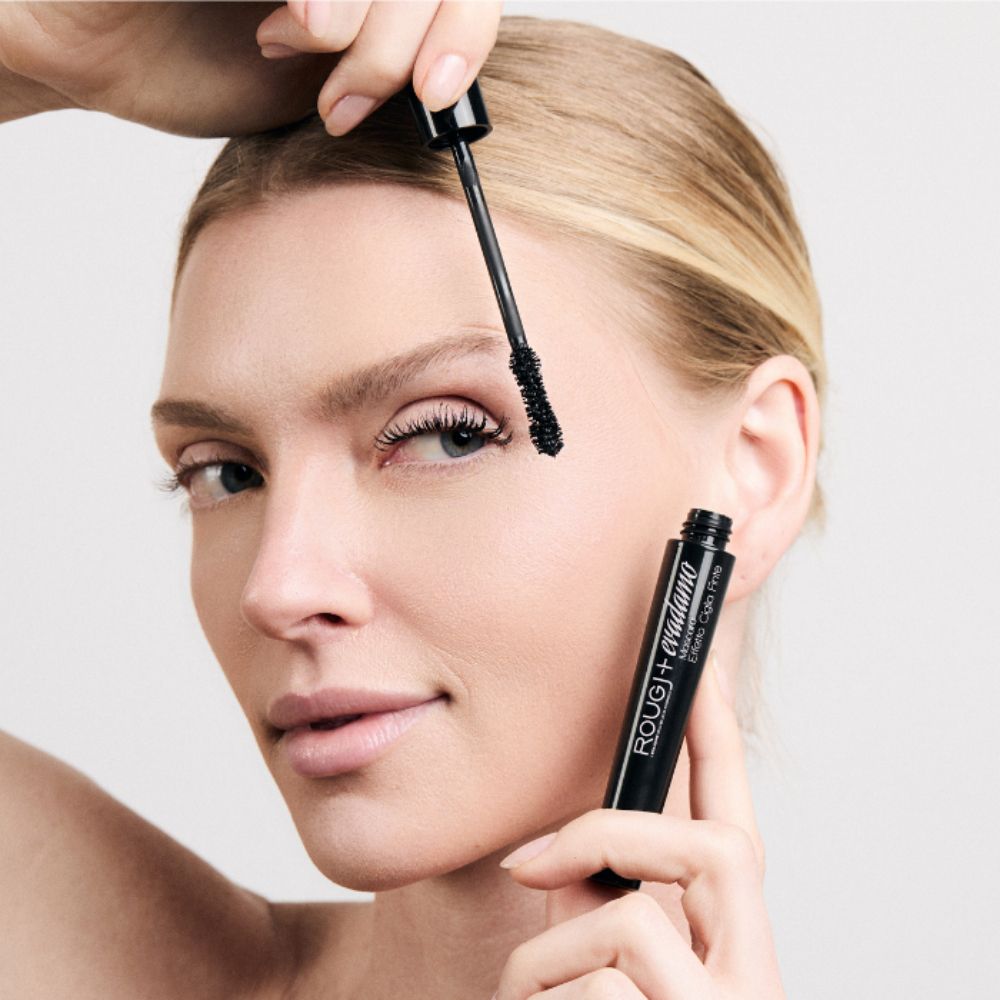 Donna applica mascara nero, tenendo tubo e applicatore.
