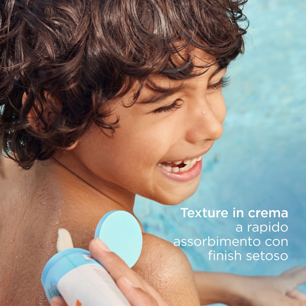 Bambino con crema solare. Texture in crema, rapido assorbimento, finish setoso. Nome prodotto non visibile.