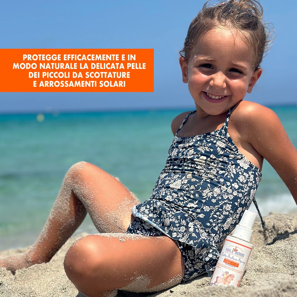 Bambina sulla spiaggia con spray solare. Flacone bianco, etichetta arancione. Scritta: Sole Bimbi, SPF 50+.