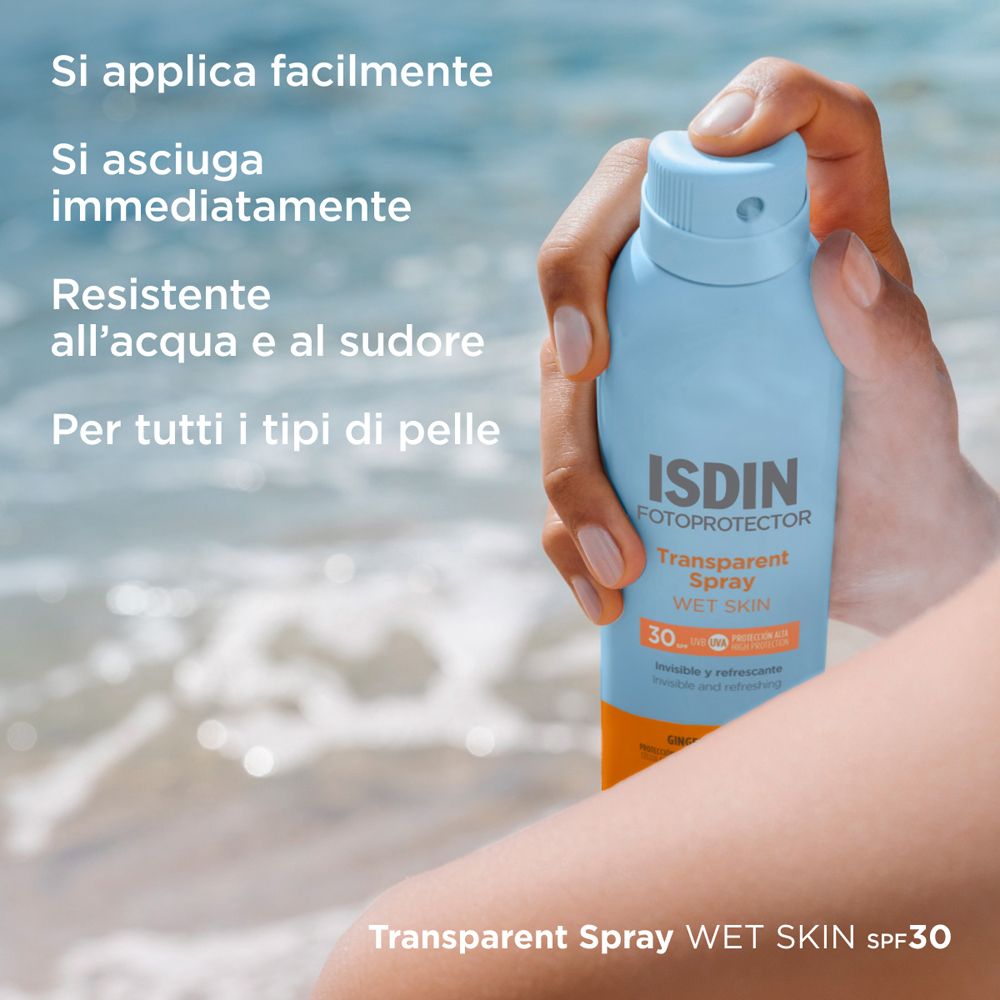 Persona che tiene un flacone spray blu. ISDIN Fotoprotector Transparent Spray Wet Skin SPF30. Testo: Facile applicazione, asciugatura rapida.