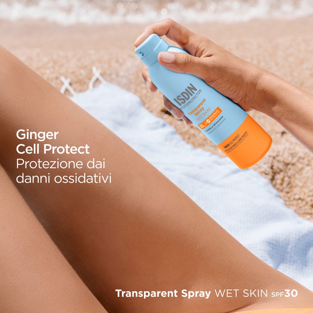 Persona che spruzza sulla gamba. ISDIN Fotoprotector Transparent Spray Wet Skin SPF30. Testo: Ginger Cell Protect.