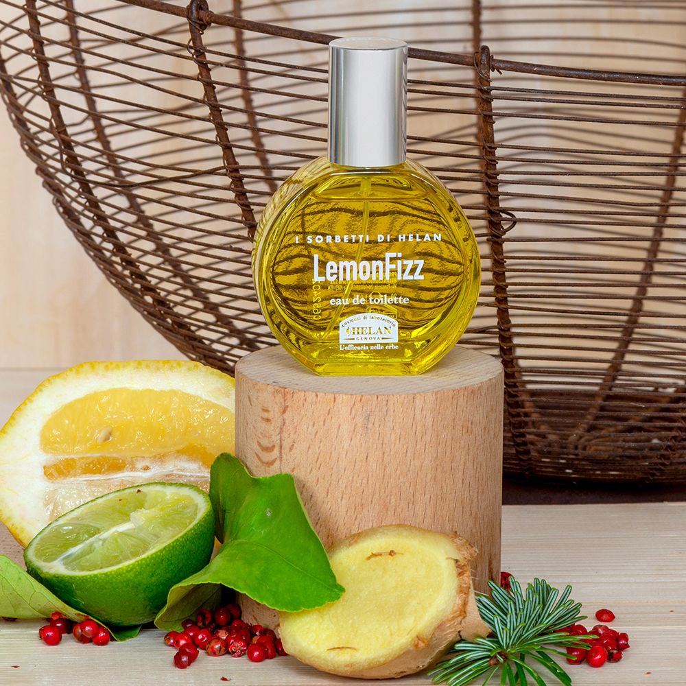 Flacone su base di legno, circondato da limoni, lime, zenzero e spezie. Cesto sullo sfondo.