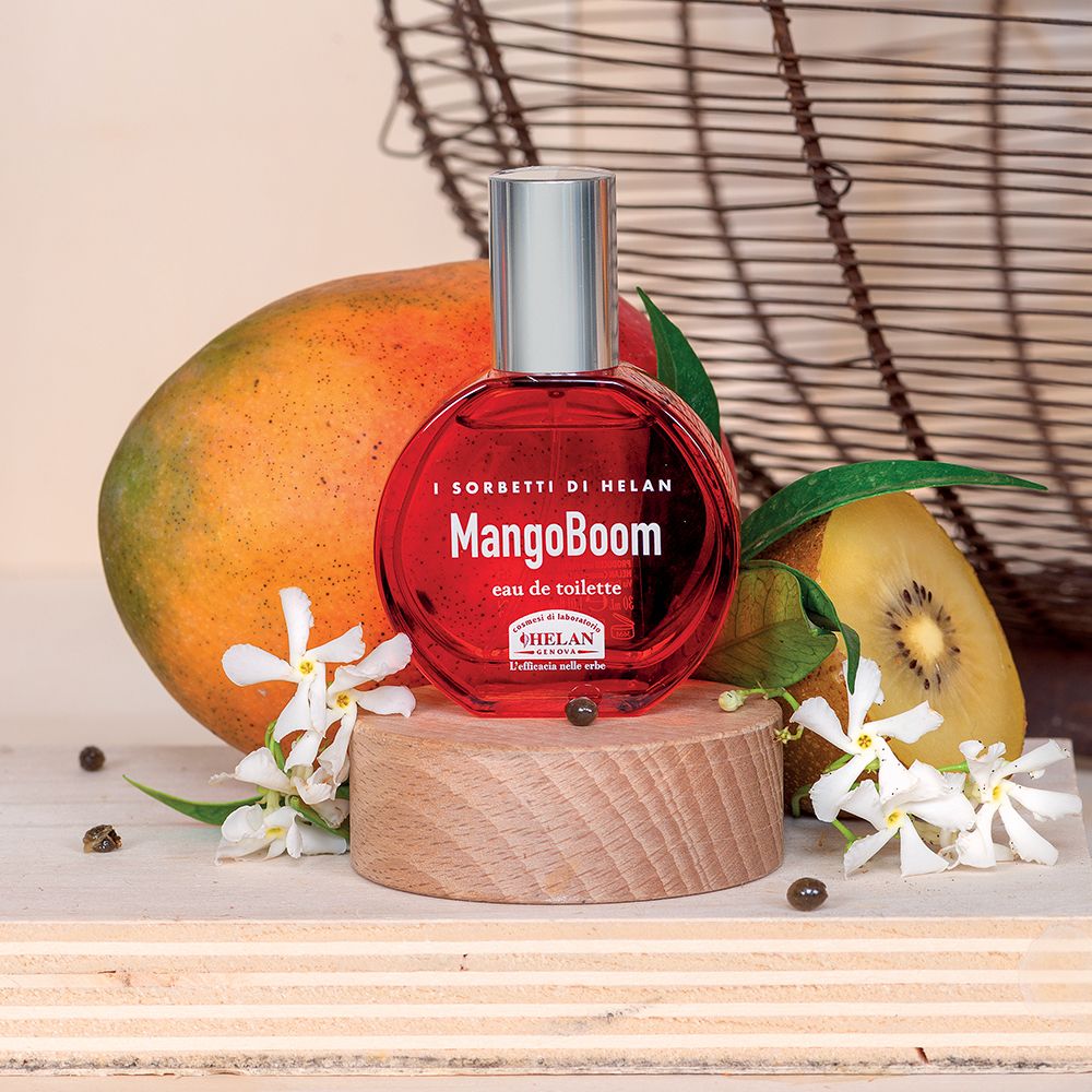Flacone rotondo su base di legno, circondato da mango, kiwi e fiori. Scritta: MangoBoom Eau de Toilette.