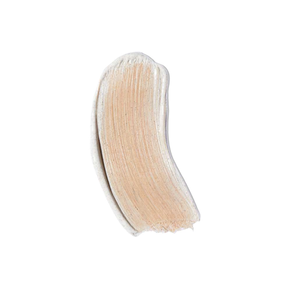 Macchia di colore chiaro. Crema con texture leggermente granulosa. Su sfondo chiaro.