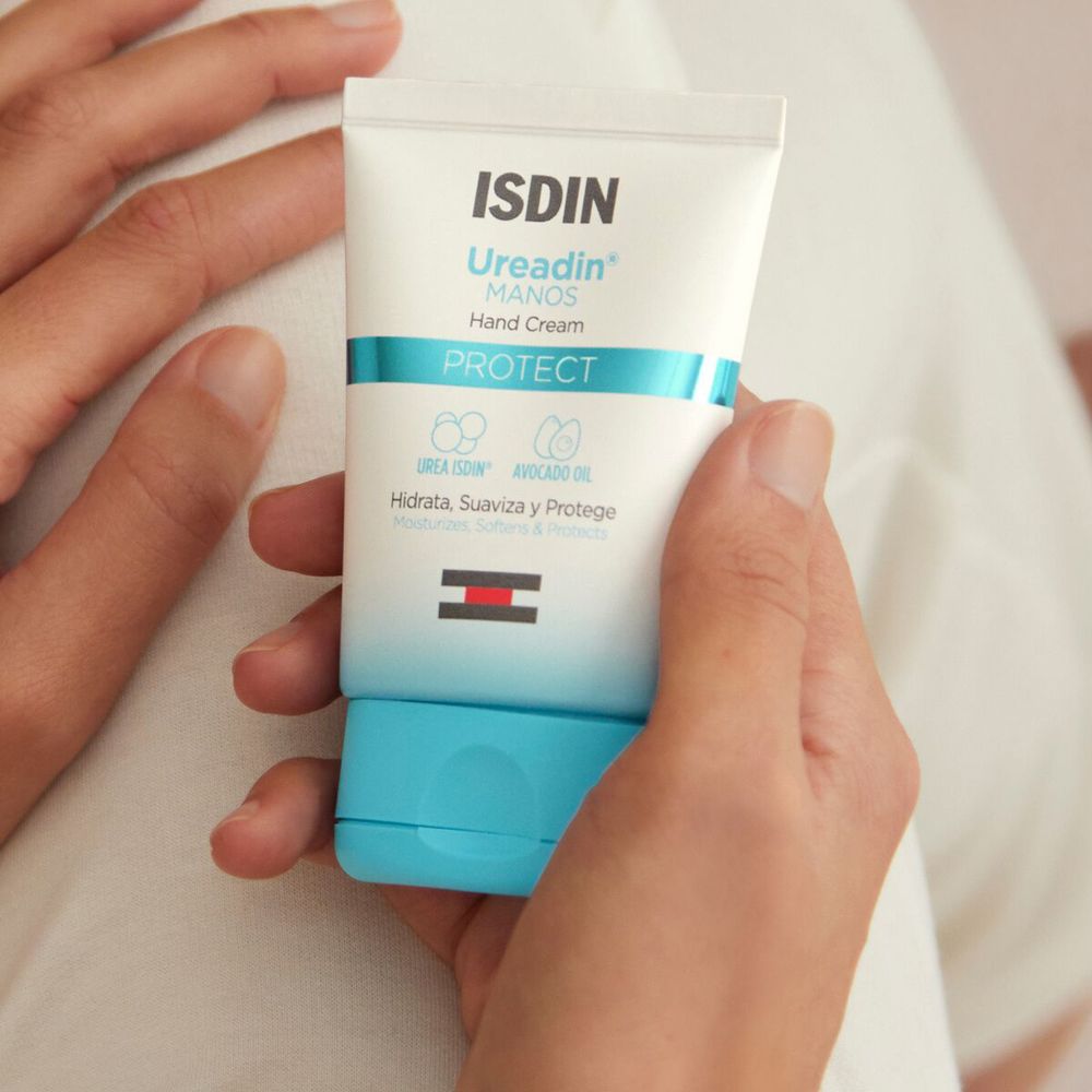 Mani che tengono un tubetto di crema. Scritta: ISDIN Ureadin MANOS Hand Cream. Strisce blu e rosse.