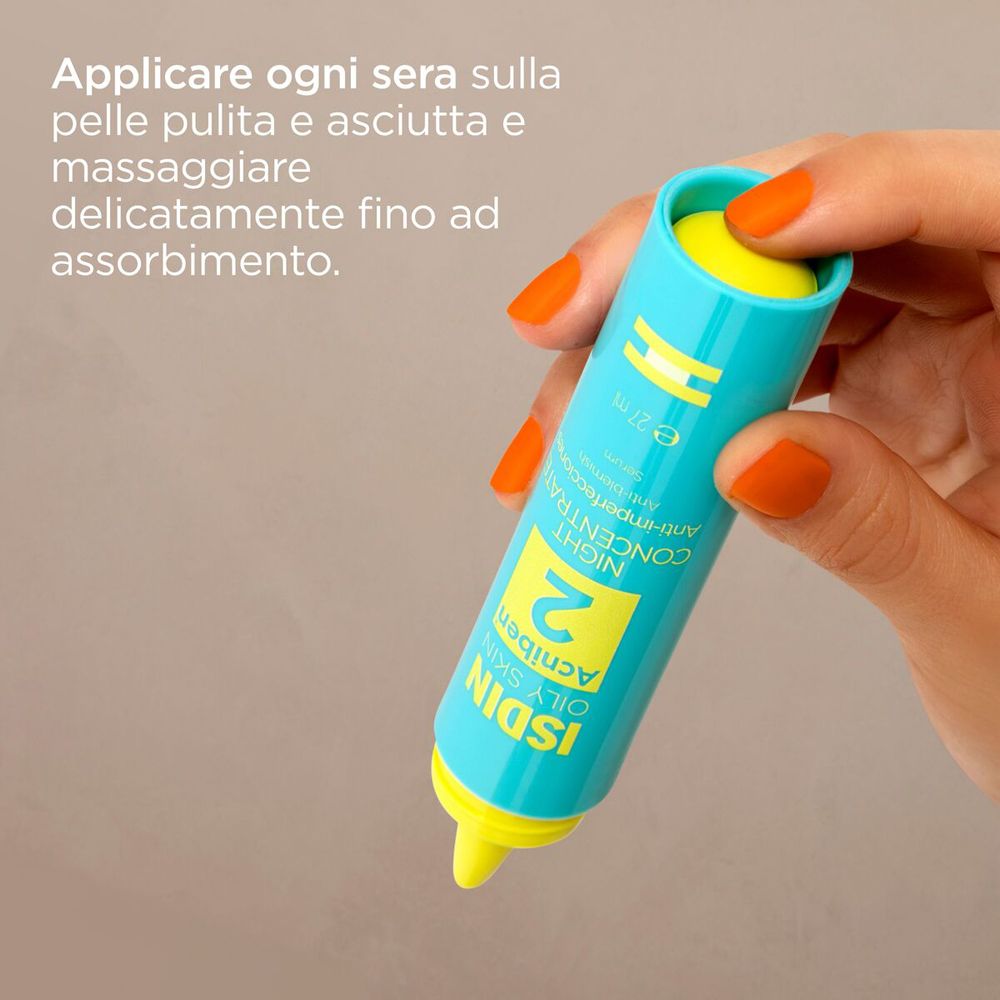 Flacone turchese con applicatore giallo. Scritta: ISDIN, Acniben 2, Night Concentrate. Mano con unghie arancioni.