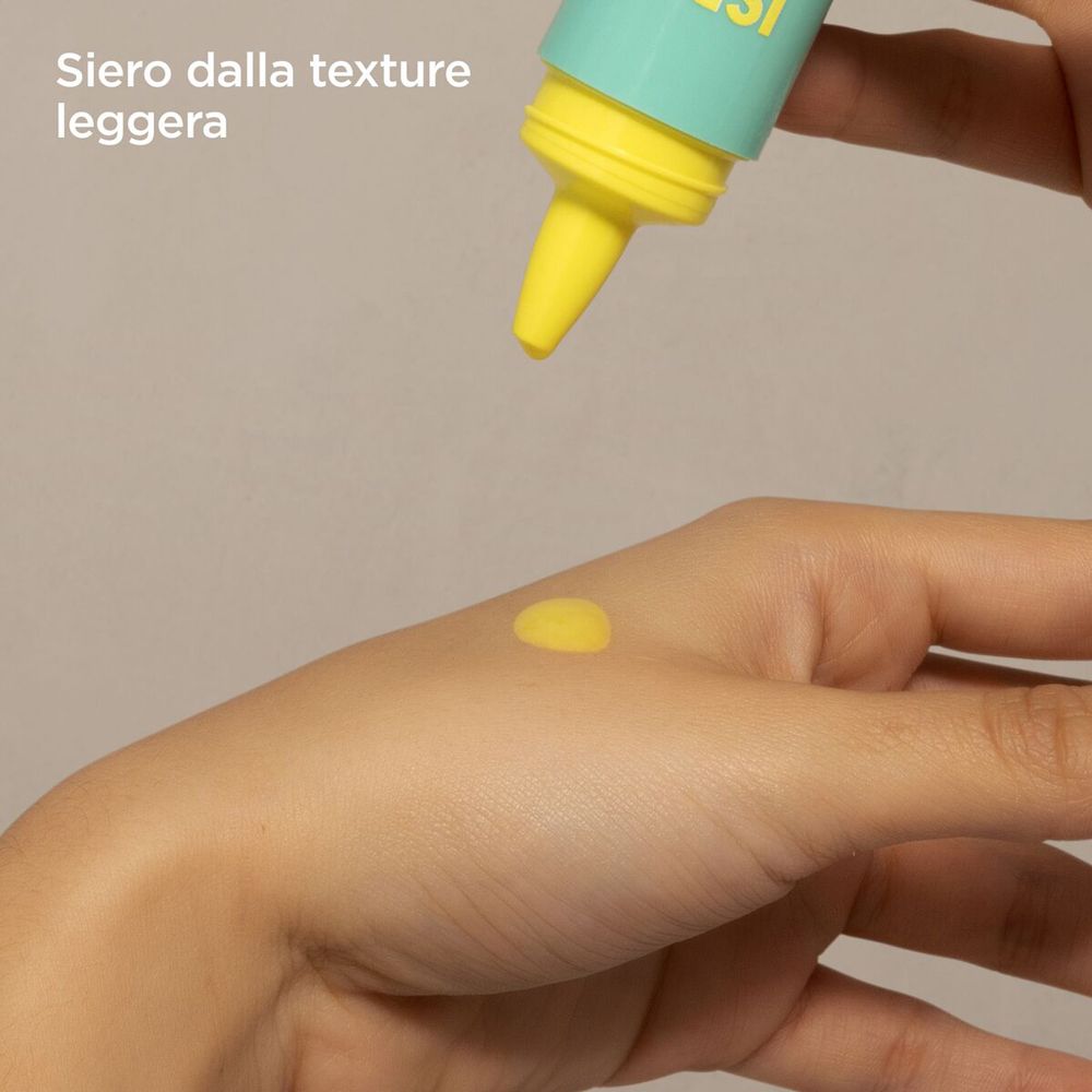 Liquido giallo su una mano. Scritta: ISDIN, Acniben 2, Night Concentrate. Primo piano.