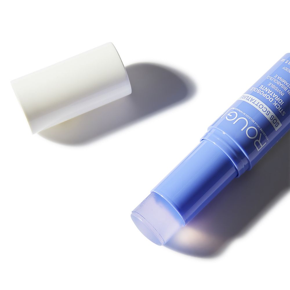 Primo piano di uno stick blu con cappuccio bianco. Scritta: ROUGJ, SOS SCOTTATURE. Lo stick è aperto.