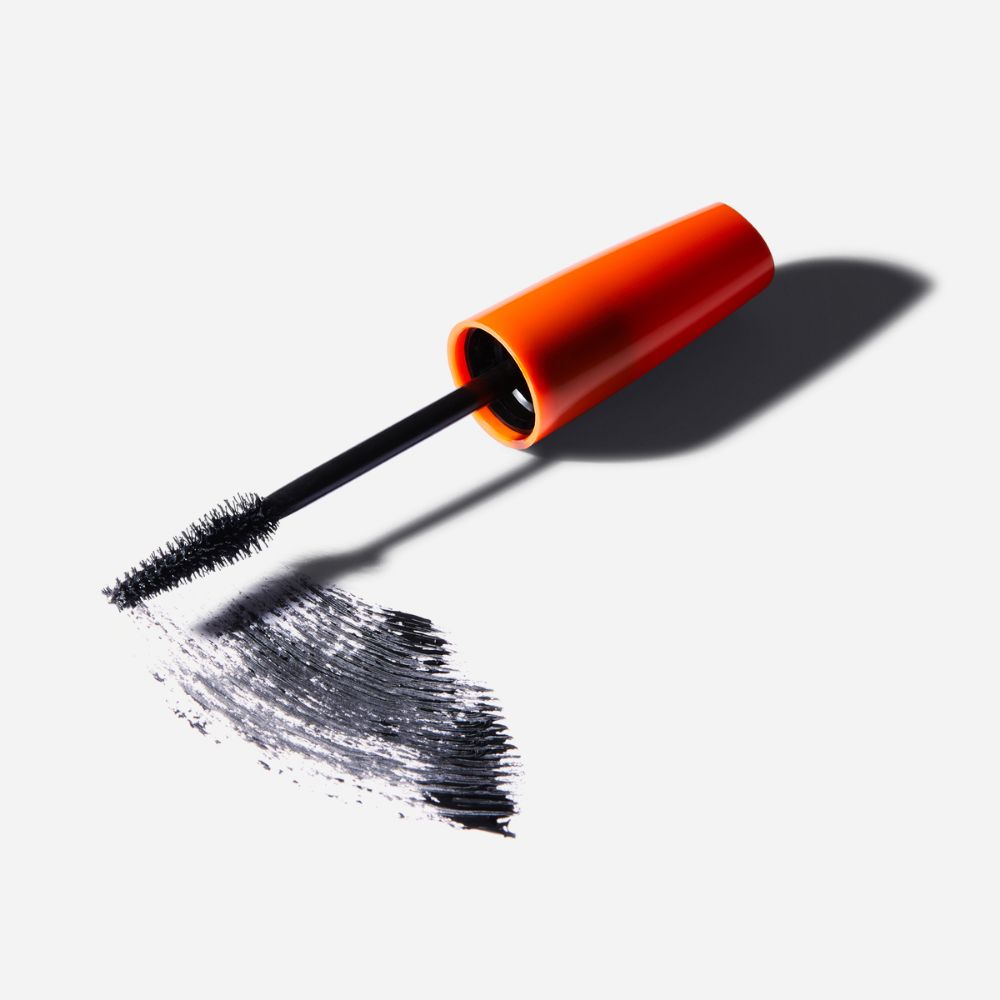 Applicatore di mascara con spazzola nera e traccia di mascara nero. Tappo arancione.