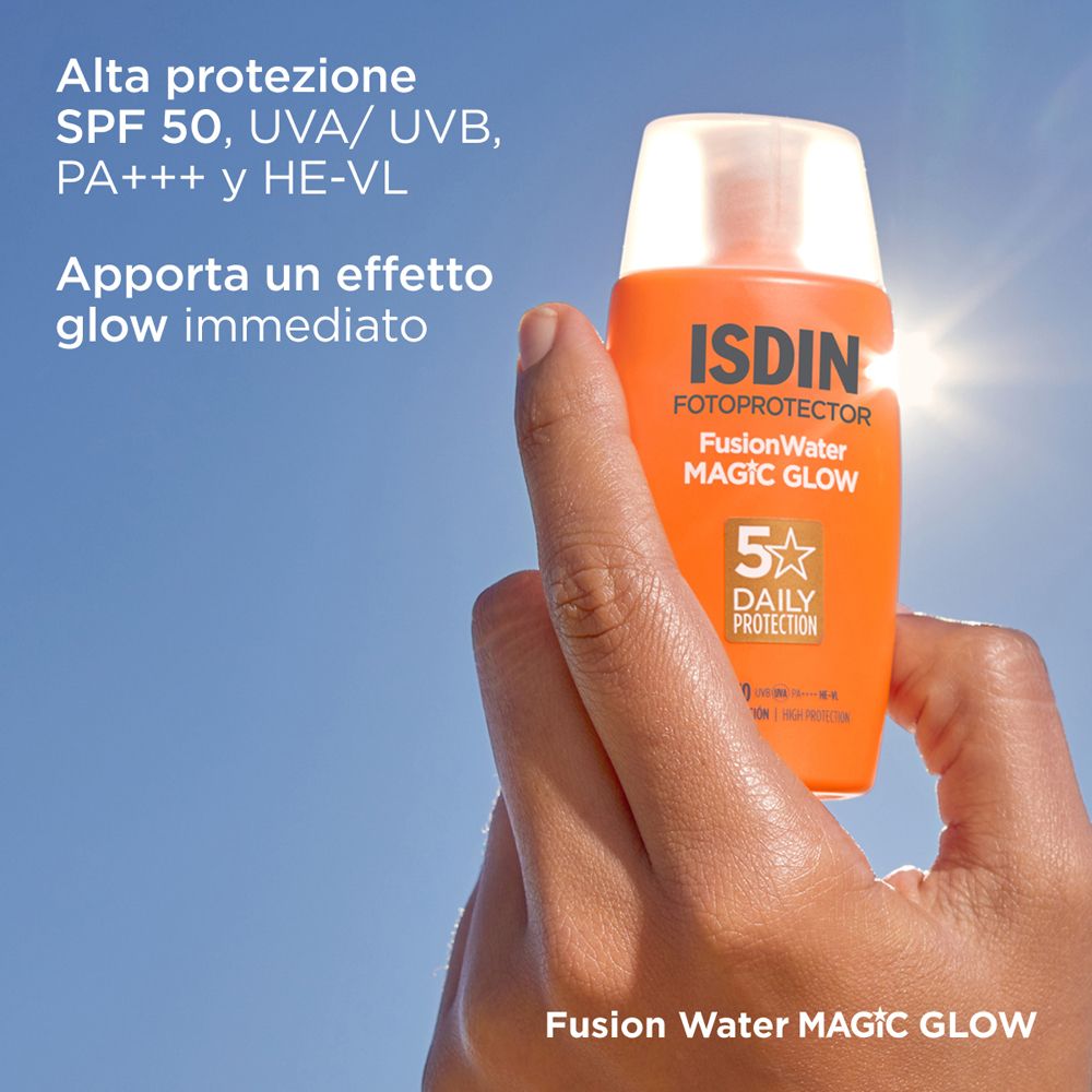Mano che tiene un flacone arancione davanti al cielo blu. Scritta: ISDIN Fotoprotector Fusion Water MAGIC GLOW.