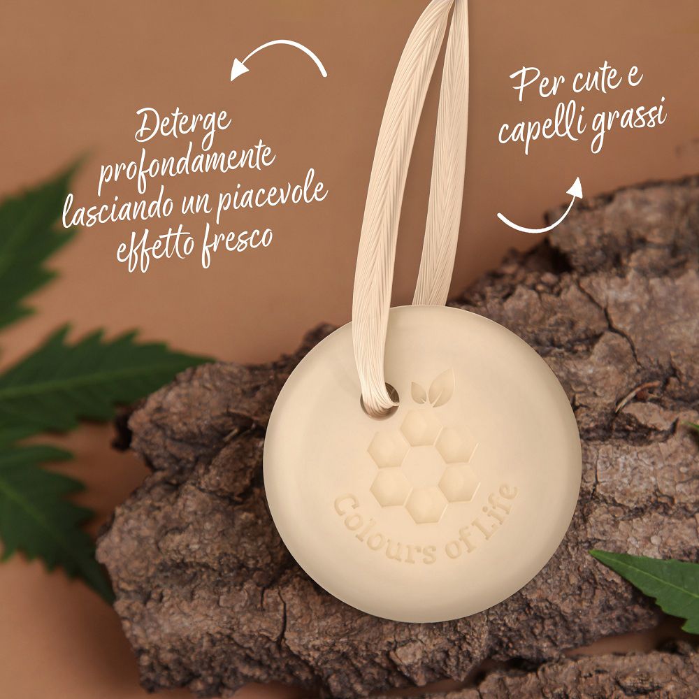 Shampoo solido rotondo al tea tree con laccetto su corteccia, con testo sulla pulizia.