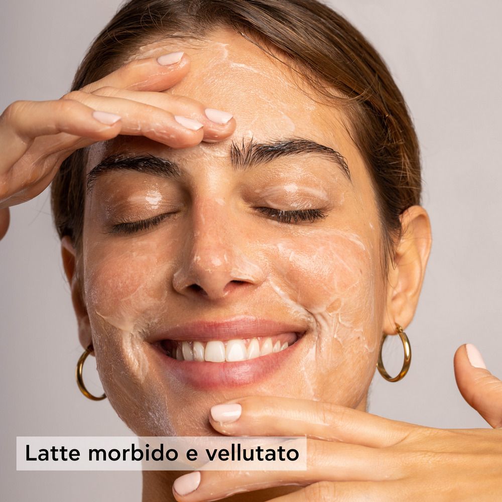 Donna con occhi chiusi, viso coperto di crema. Testo: Latte morbido e vellutato.