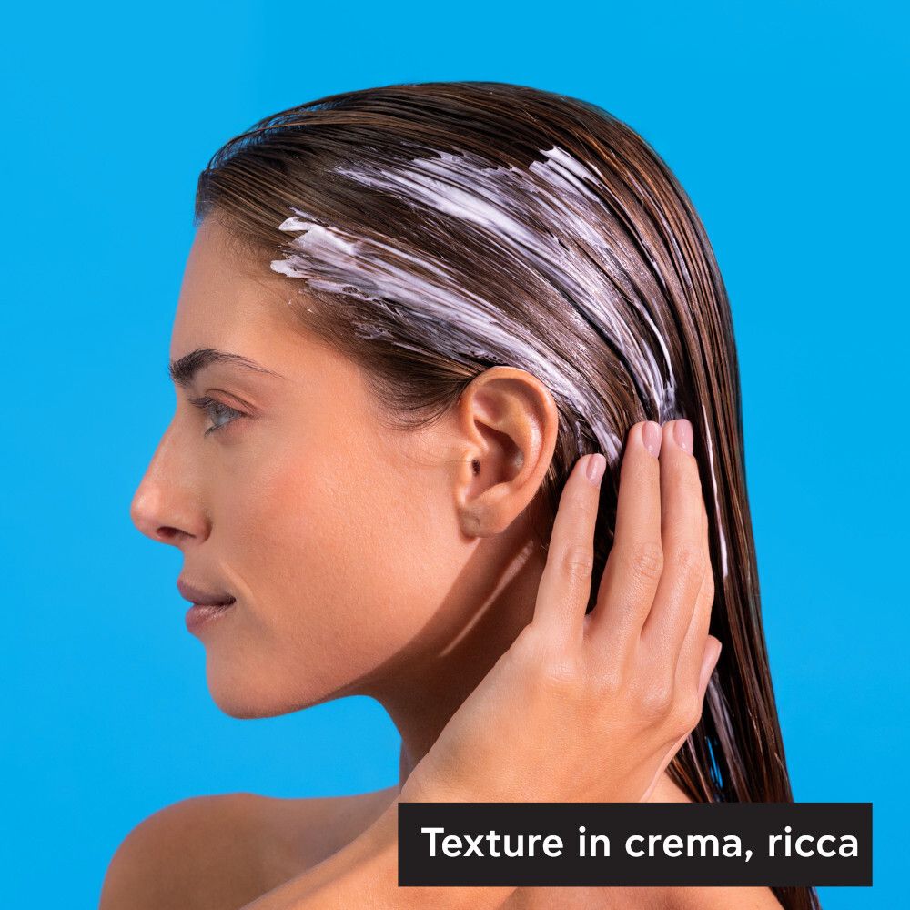 Donna con maschera per capelli. Testo: Texture cremosa e ricca. Su sfondo blu.