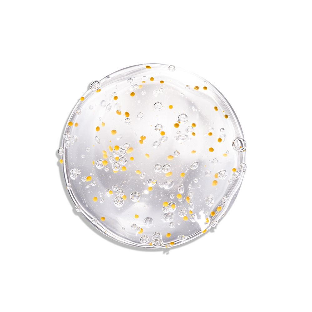 Liquido trasparente con particelle gialle. Bolle visibili. Su sfondo bianco.