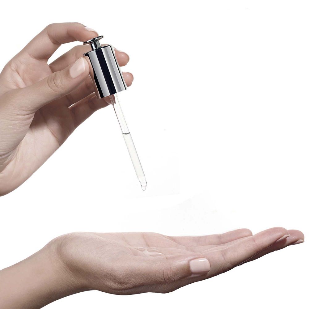 Mani che tengono una pipetta con liquido. Gocce che cadono nel palmo aperto. Sfondo bianco.