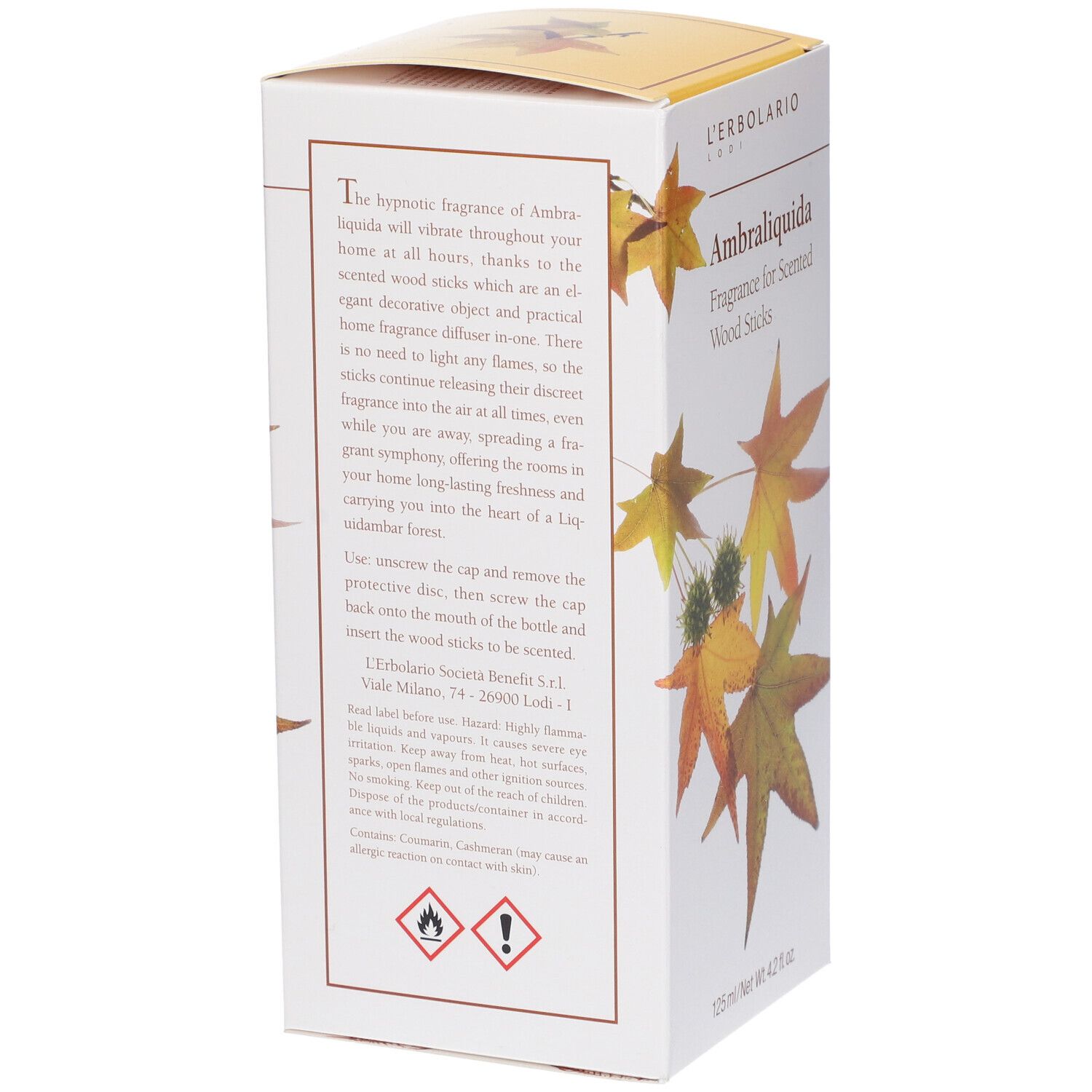 Scatola, testo sul lato. Nome del prodotto: Ambraliquida Fragrance for Scented Wood Sticks. Simboli di avvertimento e testo.