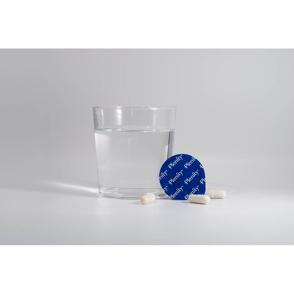 Bicchiere d'acqua, capsule e un sigillo blu accanto a una scatola blu con il logo Plenity.